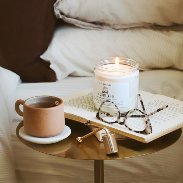 Candle on table with coffee mug. Representing our fall candle shop with the best fall scents.